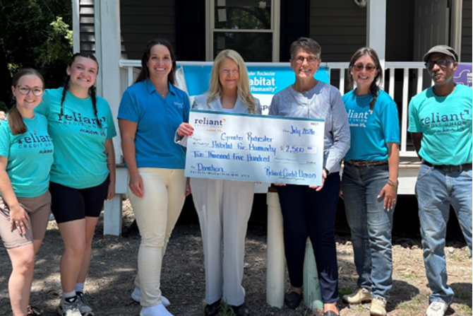 Reliant team members presenting a large donation check to the CEO of Greater Rochester Habitat for Humanity