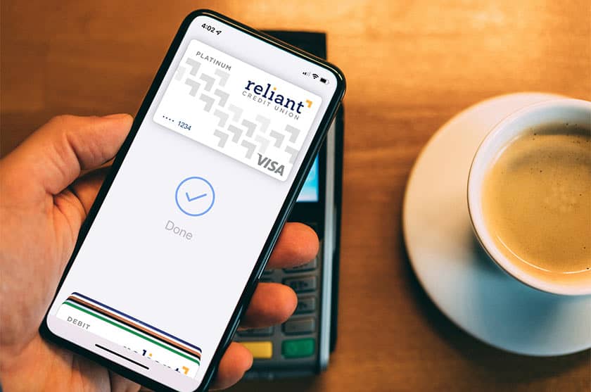Person paying for coffee with Reliant Visa credit card on mobile wallet