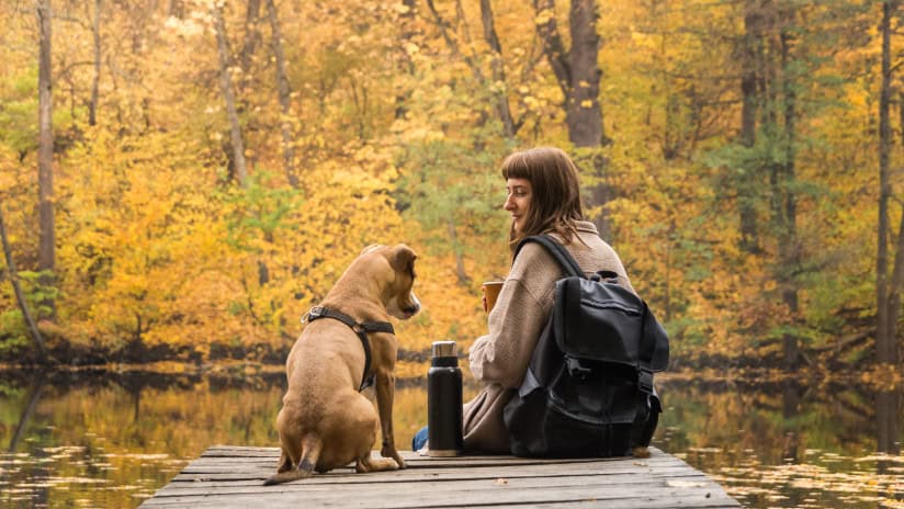 Woman sitting at pond with dog