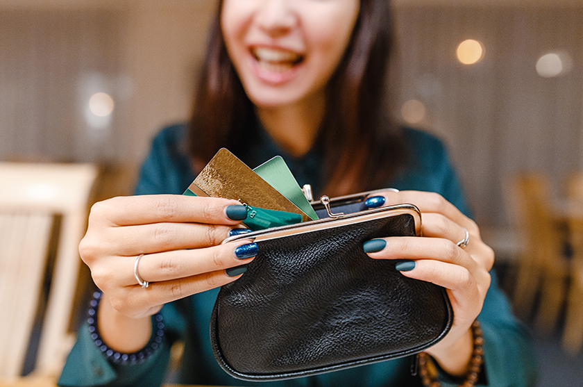 Woman holding small purse in front of her and pulling out her Visa debit card