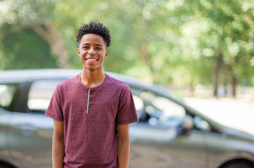 Young man standing in front of car